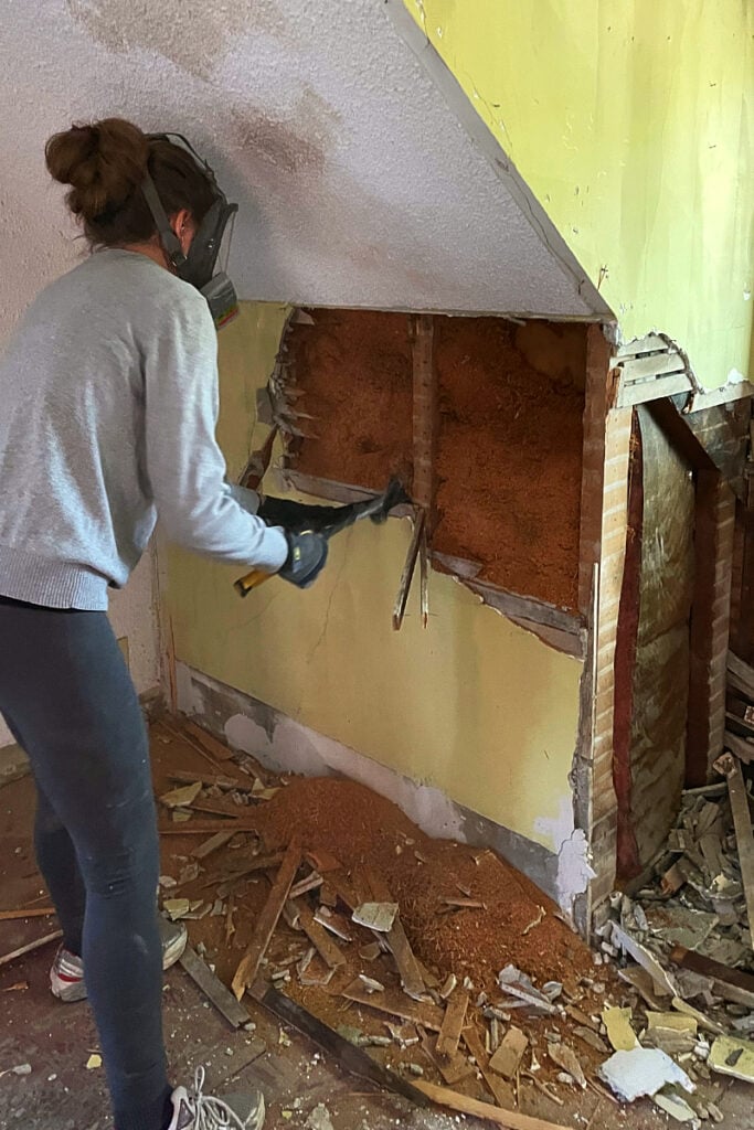 Woman using a hammer claw to demo lath and plaster
