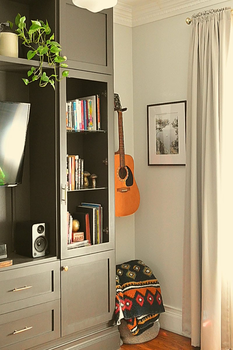 Living room corner with guitar hanging on wall and built-in shelving for books