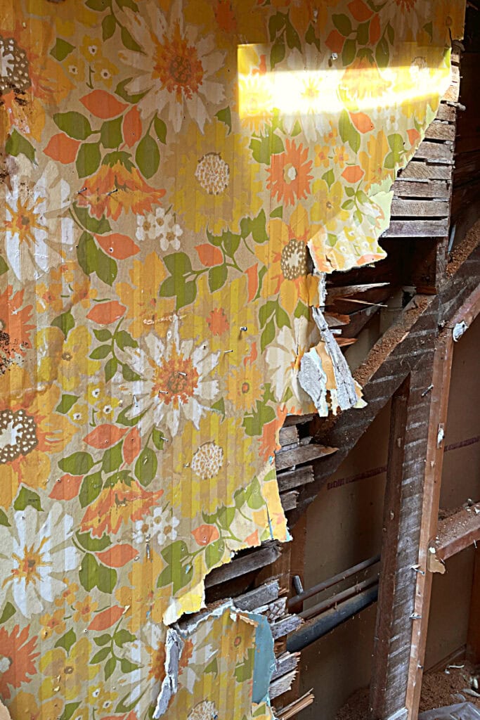 Partially demolished wall, with retro wallpaper, open to the stud